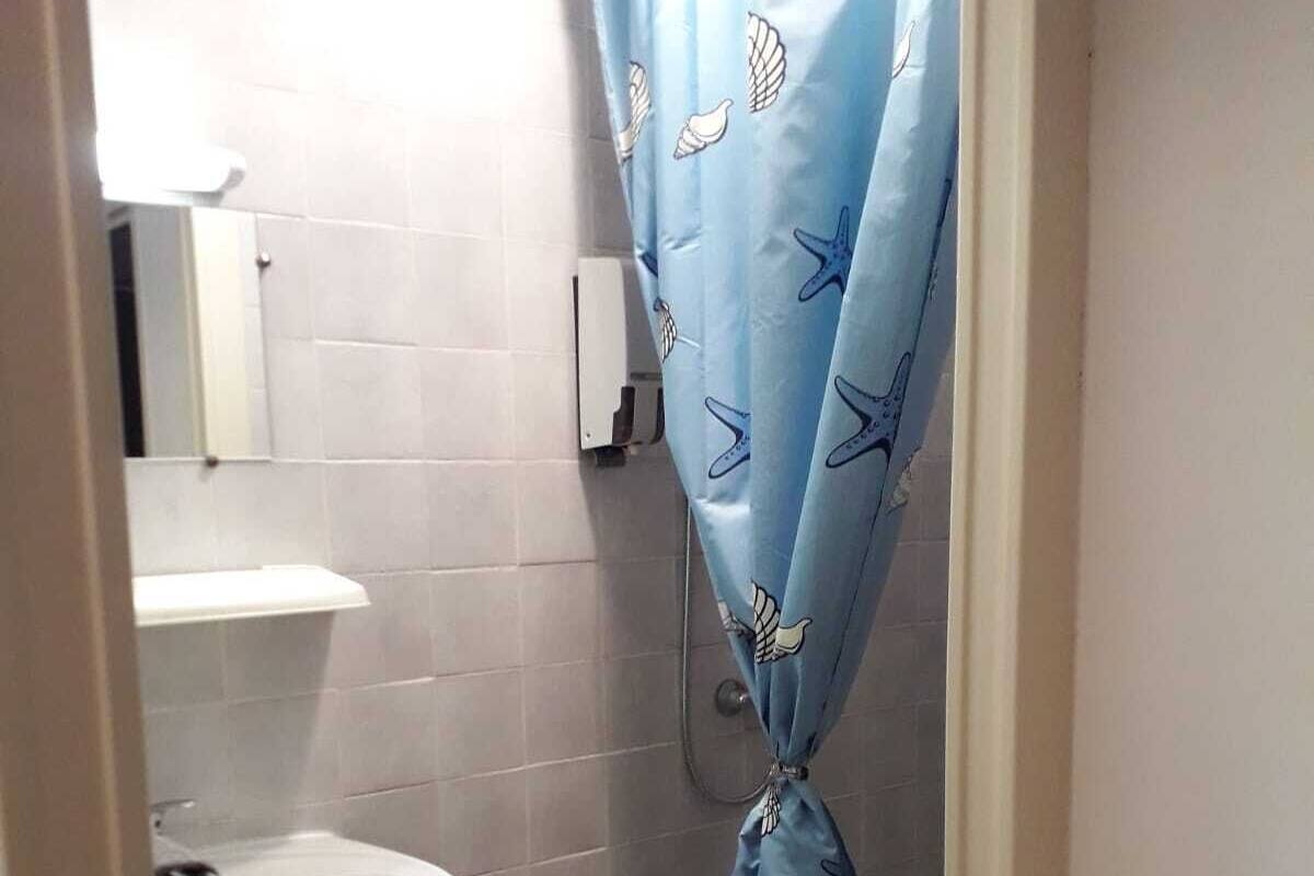A small bathroom with a white sink, a toilet, and a shower curtain with a sea-themed pattern.