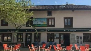 A building with a sign reading "Le Salencan" and outdoor seating with red chairs. - Le Salençon (Foissiat)