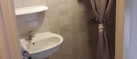 A small bathroom with a white sink, a mirror above it, and a shower curtain.