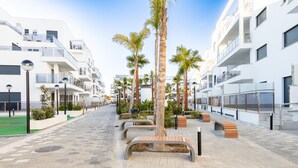 Een moderne straat in de stad met witte gebouwen, palmbomen en bankjes.