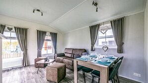 Un salon moderne avec un canapé, un pouf et une table à manger pour quatre personnes.
