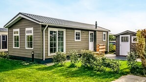 Une maison de plain-pied à l’extérieur gris, aux bordures blanches et au toit recouvert de tuiles.