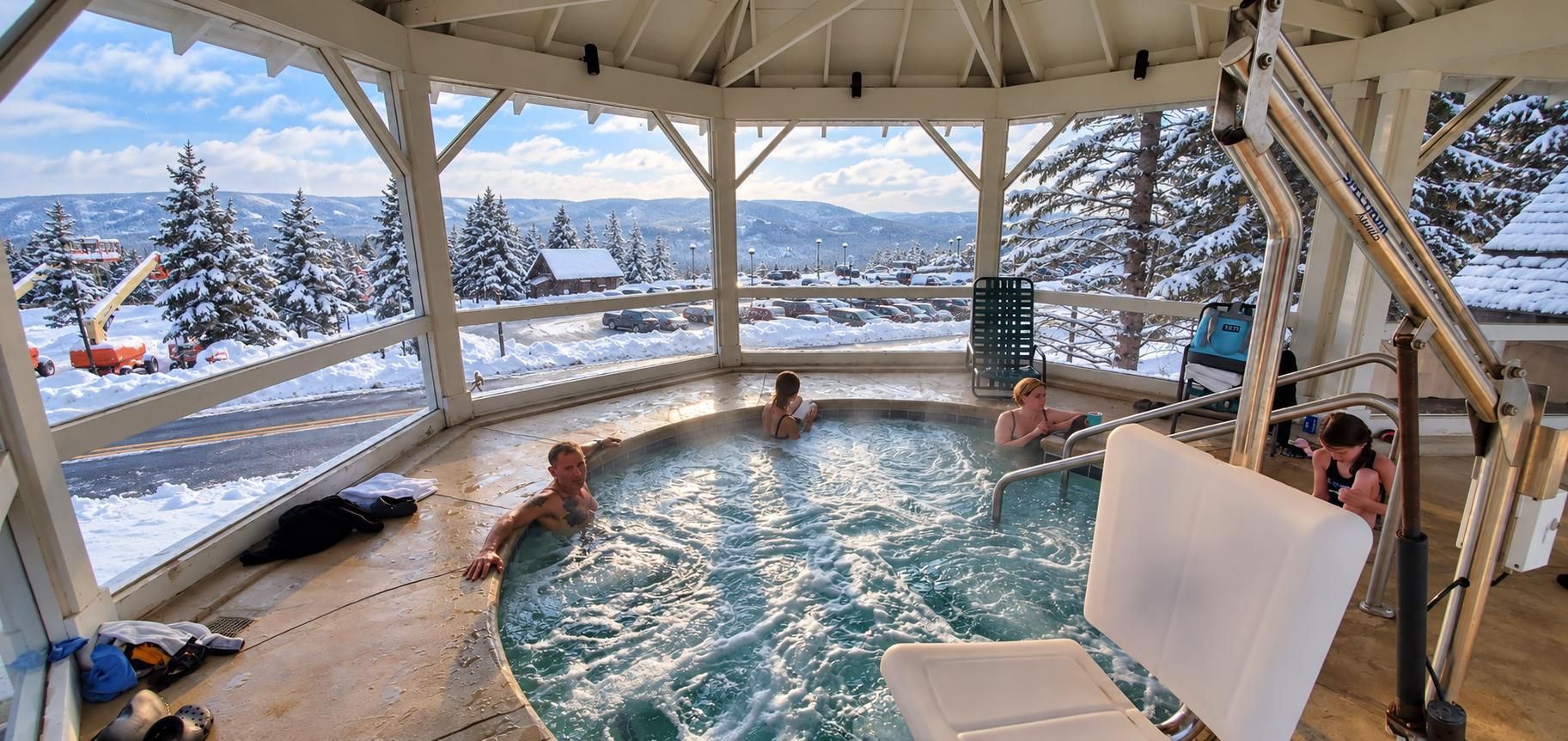 A hot tub with a view of snow-covered trees and mountains.