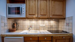 A kitchen with wooden cabinets, a microwave, a sink, and a dishwasher.