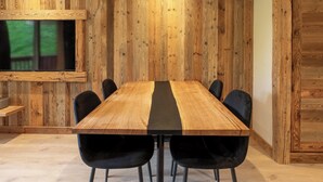 A wooden-paneled room with a central table and black chairs. - Appartement ski in and out in the center of Méribel (Les Allues)
