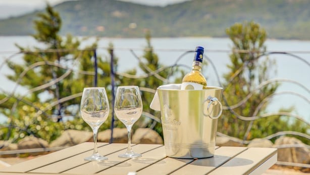 Une table avec deux verres à vin et une bouteille de champagne dans un seau en métal.
