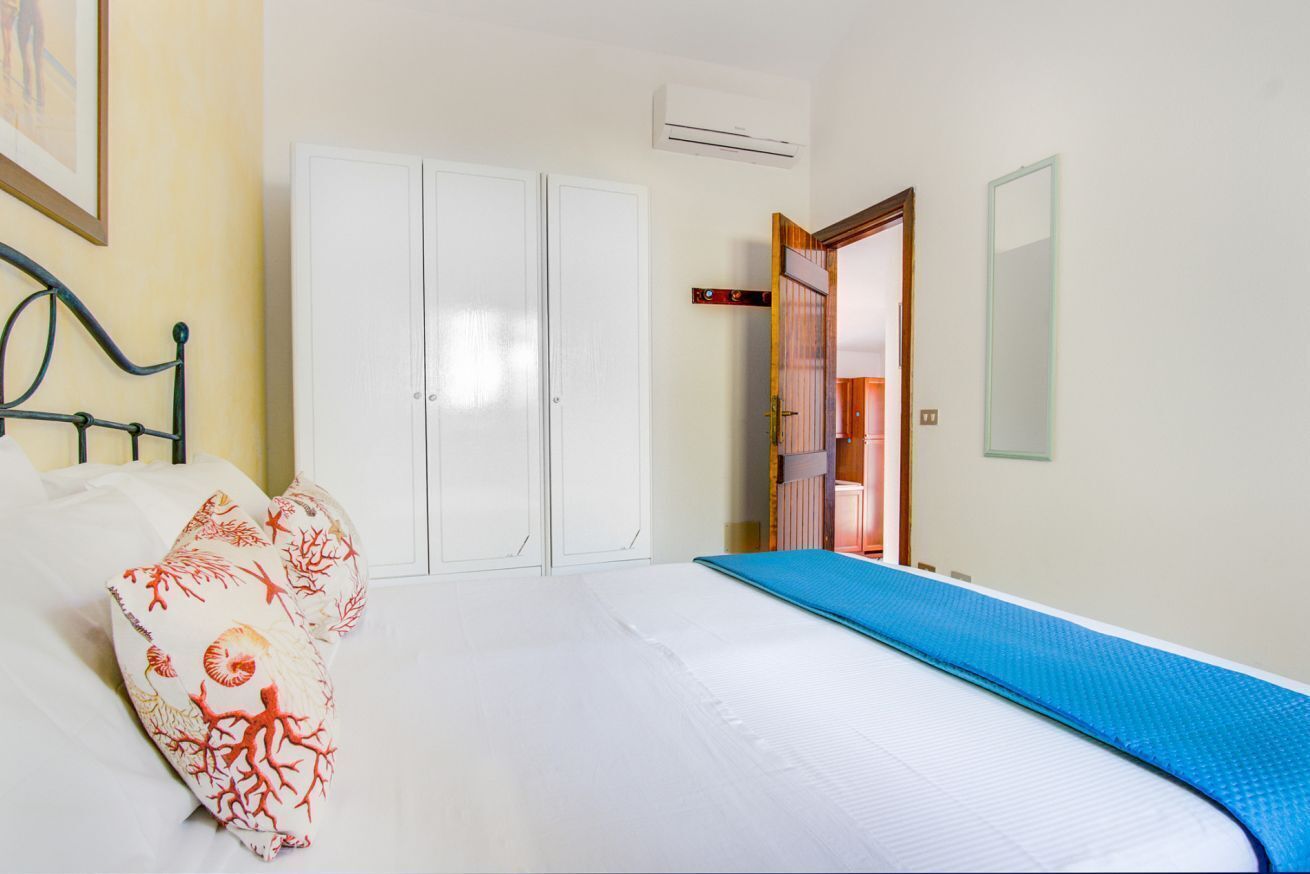 A bedroom with a bed, white wardrobe, and a door leading to a bathroom.