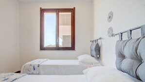 Een slaapkamer met twee bedden, een raam met zonwering en decoratieve spiegelwanden.