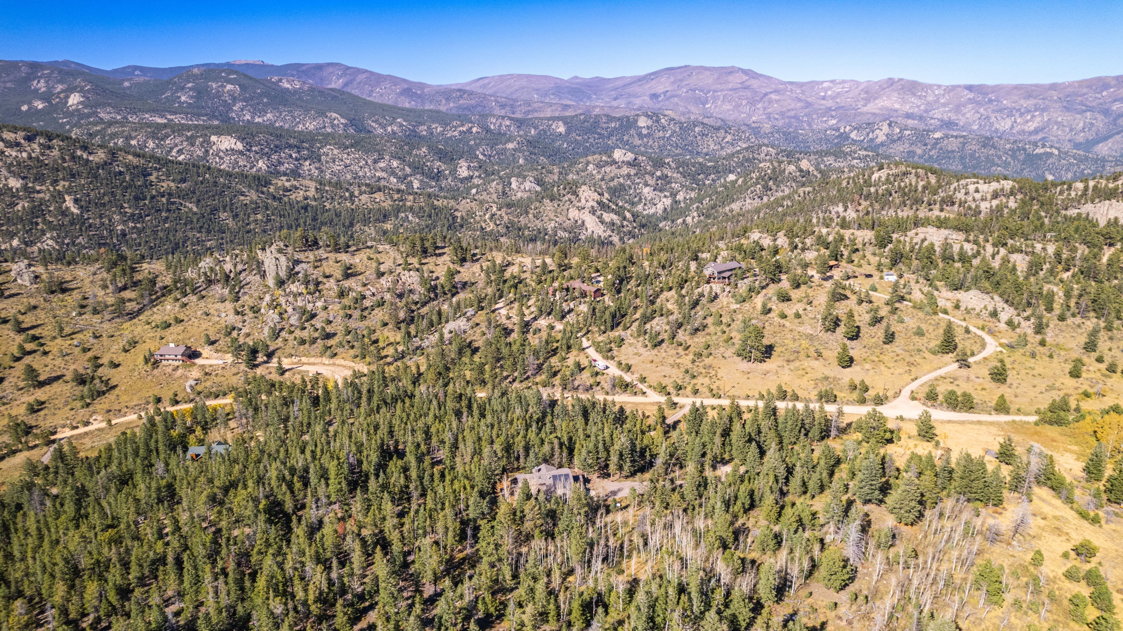 Un paisaje montañoso con casas dispersas y bosques densos.