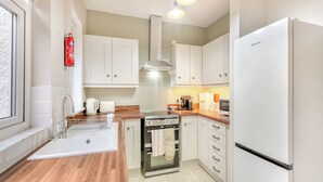A modern kitchen with white cabinets, a stainless steel oven, a built-in microwave, and a refrigerator. - Pennypot Cottage - UK41787 (Kettlewell)
