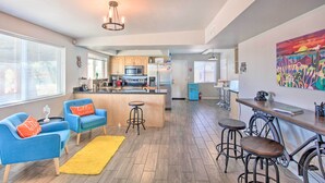 A modern kitchen with a central island, bar stools, and a dining area with a bicycle. - Vibrant, Colorful Tucson Abode w/ Pool & Hot Tub (Tucson)