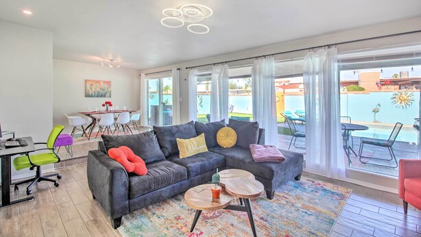 A modern living room with a gray sectional sofa, a coffee table, and a dining area with a table and chairs. - Vibrant, Colorful Tucson Abode w/ Pool & Hot Tub (Tucson)