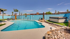 A rectangular swimming pool with a light blue interior, surrounded by a light-colored deck. There are two lounge chairs and a hot tub on the deck. - Vibrant, Colorful Tucson Abode w/ Pool & Hot Tub (Tucson)
