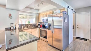 A modern kitchen with granite countertops, stainless steel appliances, and wooden cabinets. - Vibrant, Colorful Tucson Abode w/ Pool & Hot Tub (Tucson)