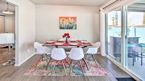 A dining area with a table set for four, white chairs, a colorful rug, and a painting on the wall. - Vibrant, Colorful Tucson Abode w/ Pool & Hot Tub (Tucson)