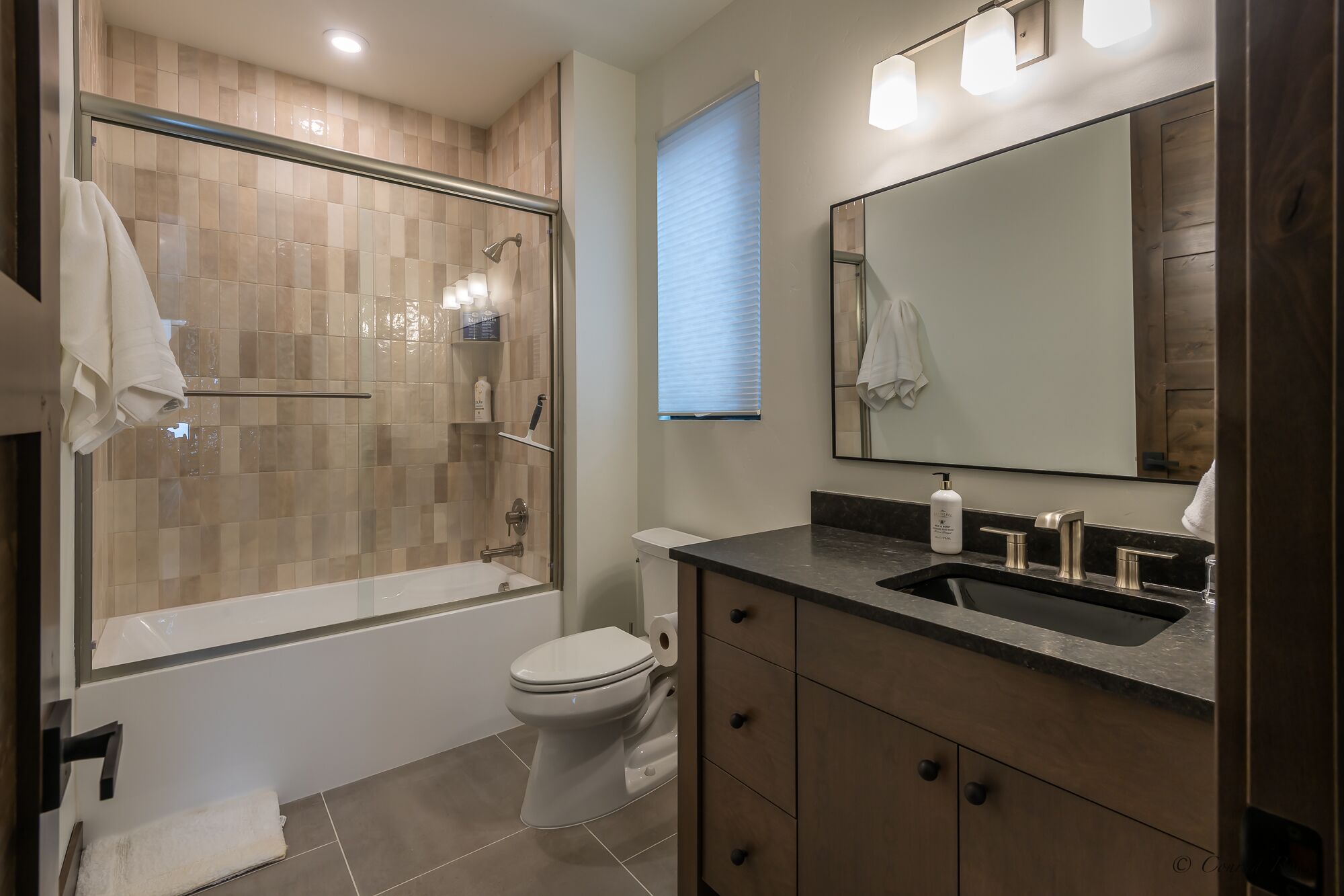 Une salle de bain moderne dotée d’une douche à parois de verre, de toilettes et d’un meuble-lavabo avec un évier et un miroir.