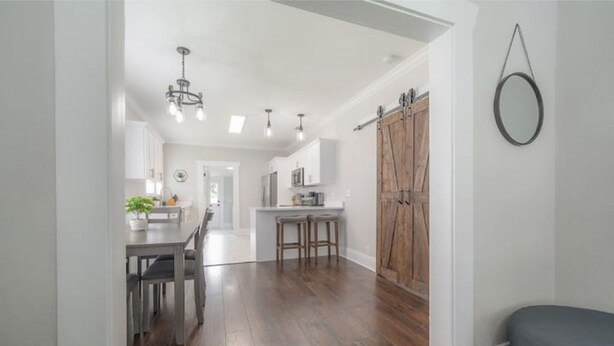 A modern kitchen with a central island, wooden flooring, and pendant lighting.
