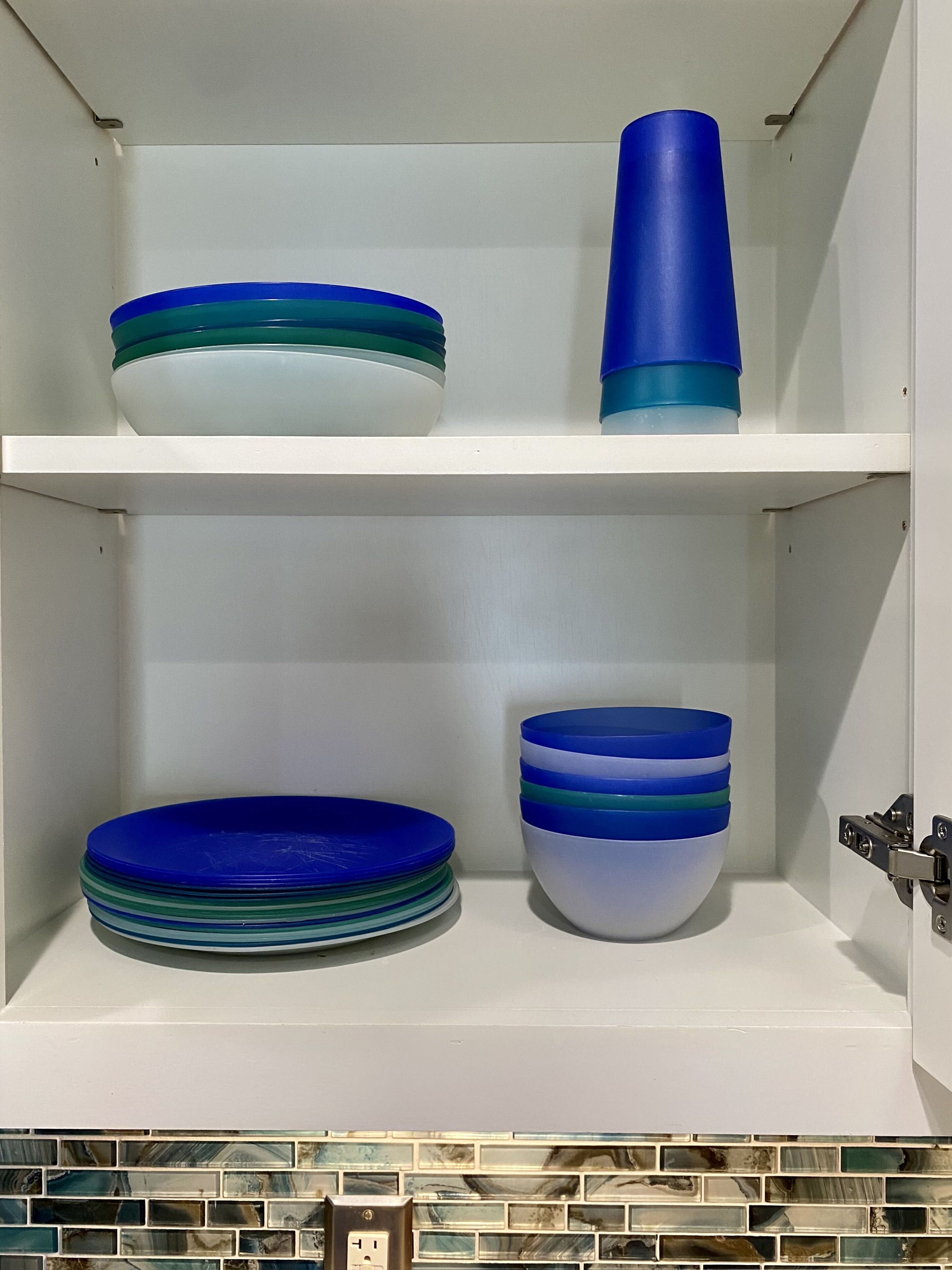 Une étagère de cuisine avec des assiettes et des bols bleus et blancs empilés.