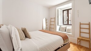 Un dormitorio con cama, ventana con vistas y escalera de madera.