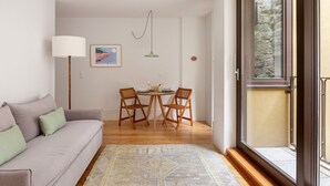 Una sala moderna con un sofá, una mesa de comedor con sillas, una lámpara y un cuadro en la pared.
