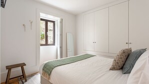 A bedroom with a bed, a wardrobe, a small stool, and a window. - JOIVY Stunning 1-bed flat with balcony (Porto)