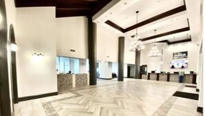 A spacious lobby with a herringbone floor pattern, a reception desk, and a chandelier. - Beachfront Wrap Balcony & Views! Shores of Panama (Panama City Beach)