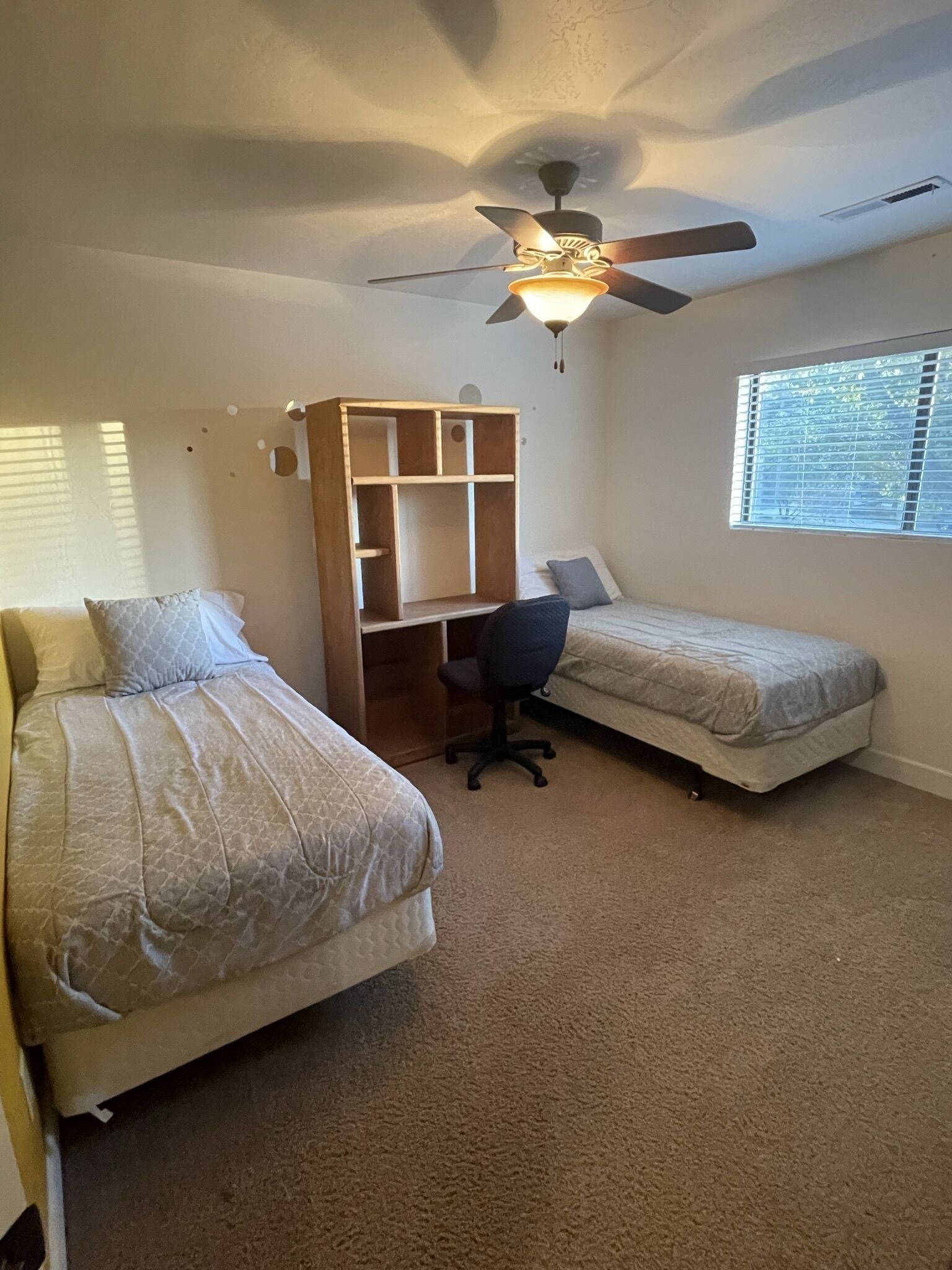 Ein Schlafzimmer mit zwei Betten, einem Schreibtisch und einem Deckenventilator.