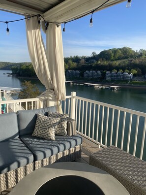 Un balcon avec un canapé, des meubles en osier et une vue sur un lac et des bâtiments.