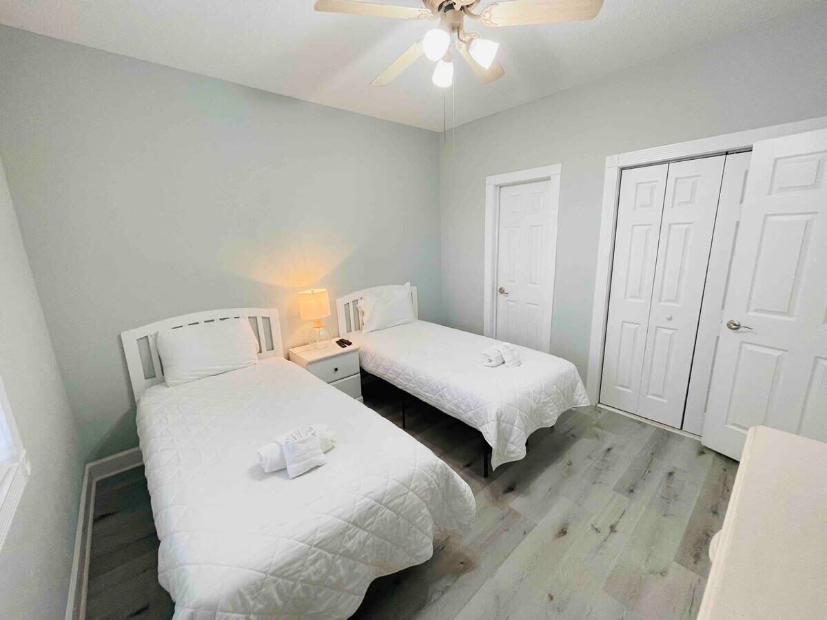 A bedroom with two single beds, a ceiling fan, and white doors.