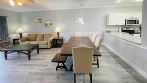 A modern living room with a dining table, sofas, and a kitchen area with cabinets and appliances. - Super Comfortable condo in center of Myrtle Beach (Myrtle Beach)