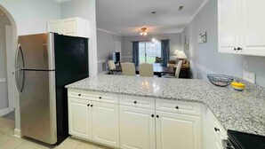A kitchen with white cabinets, a granite countertop, and a stainless steel refrigerator. - Super Comfortable condo in center of Myrtle Beach (Myrtle Beach)