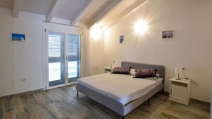 Un dormitorio con cama, mesita de noche, lámpara y puerta con paneles de vidrio.