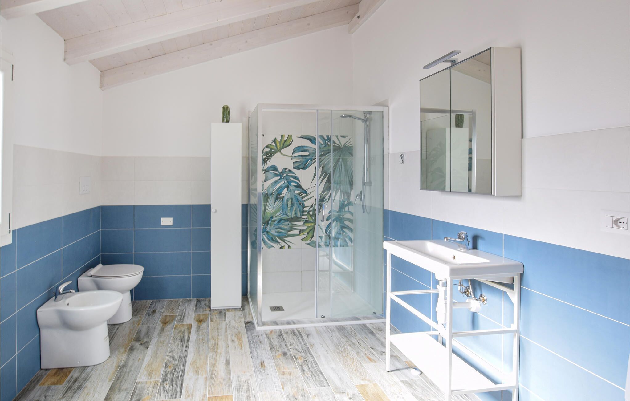A bathroom with a shower, toilet, bidet, and sink.