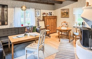 A cozy room with a wooden table, chairs, a fireplace, and a window with curtains. - Gorgeous home in Hok with WiFi (Hok)
