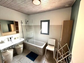 A modern bathroom with a bathtub, a shower, a sink, and a mirror.