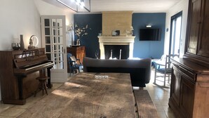 Un salón amplio con un piano, una chimenea, un sofá y una mesa de comedor.