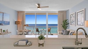 A modern hotel room with a balcony, a dining area, and a kitchen with a sink. - BeachFront-Ocean View at Majestic Beach Resort #906 (Panama City)