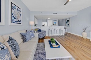 Uma sala de estar moderna com sofá, mesa de centro e área de cozinha com banquetas.