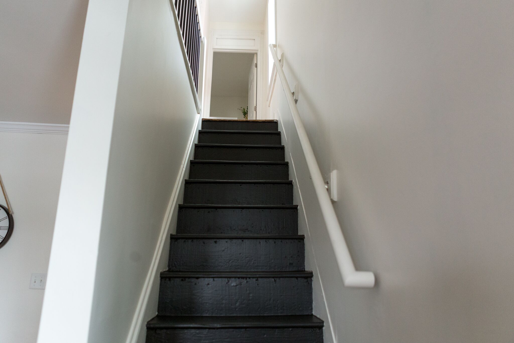 Una escalera con peldaños negros y paredes blancas.
