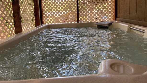 A hot tub with water, surrounded by wooden beams and a lattice fence. - Pet friendly Fun Family Cabin- 3 Beds, Fireplace, Horseshoes, Swing, Hottub (Payson)
