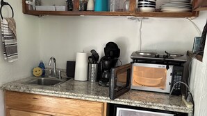 A compact kitchen with wooden cabinets, a granite countertop, a built-in microwave, a coffee maker, and a dish rack. - Pet friendly Fun Family Cabin- 3 Beds, Fireplace, Horseshoes, Swing, Hottub (Payson)
