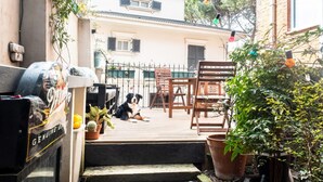 Een terras met tuinmeubilair, een barbecue en plantenpotten.