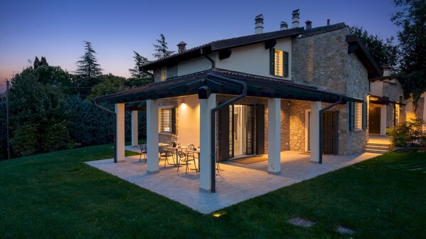 A house with a covered patio area, stone walls, and a well-maintained lawn. - Villa Pergola 8 in Bologna (Castel San Pietro Terme)