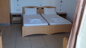 Een tweepersoonsbed met een houten hoofdeinde, twee nachtkastjes, een wandlamp en een bloemen schilderij aan de muur.