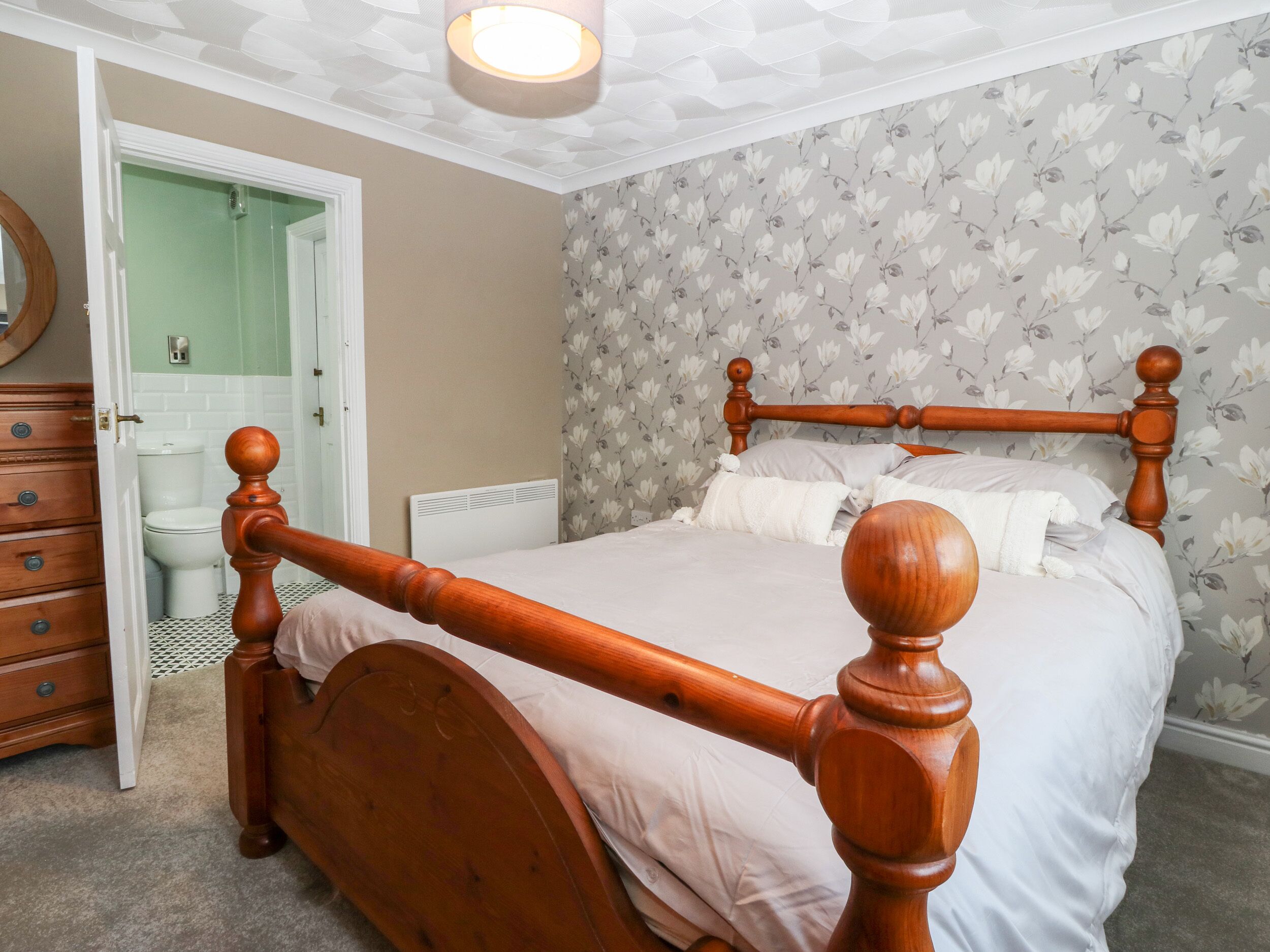 A bedroom with a wooden bed, a dresser, a toilet, and a shower.