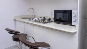 Une cuisine compacte équipée d’un four à micro-ondes, d’un évier et d’une cuisinière à gaz.