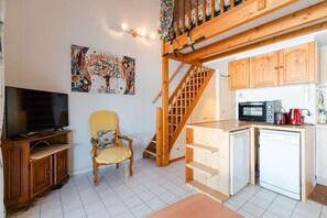 Cozy living space with a kitchenette, television, and staircase leading to an upper level.