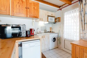 Compact kitchen with a microwave, kettle, coffee maker, dishwasher, and washing machine.