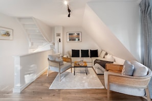 Un loft moderno con escalera, un conjunto de sofás, una mesa de centro y una estantería.