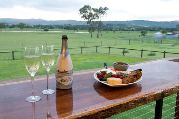Une table avec deux verres de vin blanc, une bouteille de vin et une assiette de fromage et de crackers.
